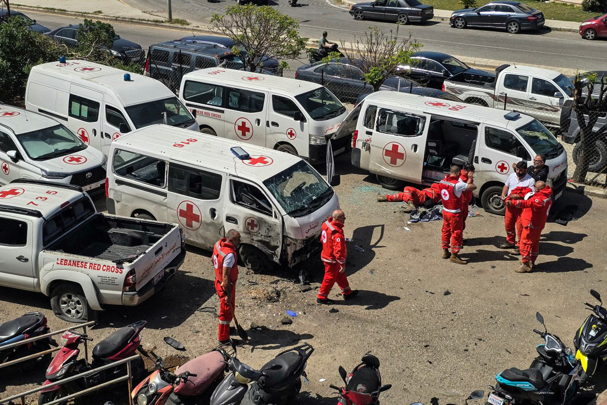 Lebanese Red Cross volunteers inspect the damage to their rescue ambulances at the site of an Israeli drone strike that targeted their headquarters in the southern city of Tyre on April 13, 2026. (AFP)