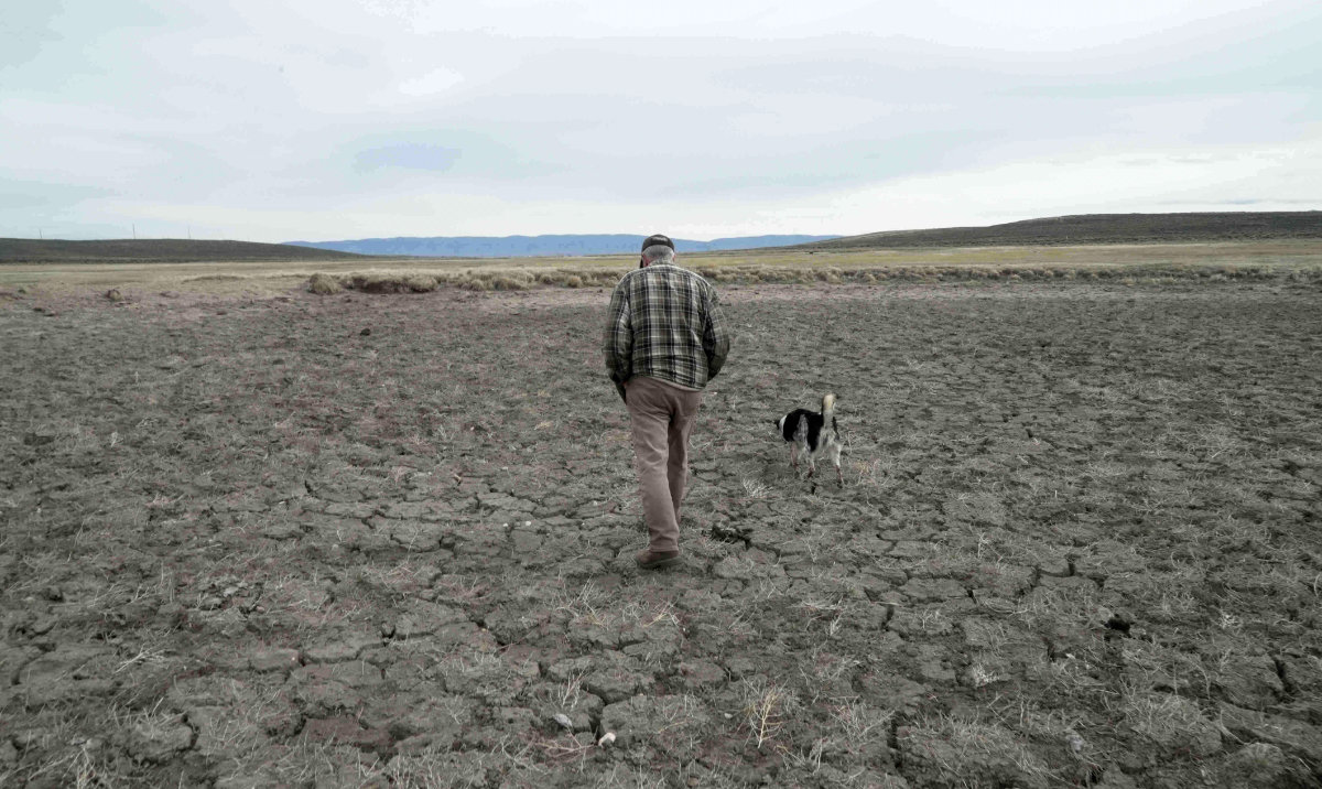 Philip Anderson walks across a dry stock pond March 31, 2026, in Walden, Colo. (AP)