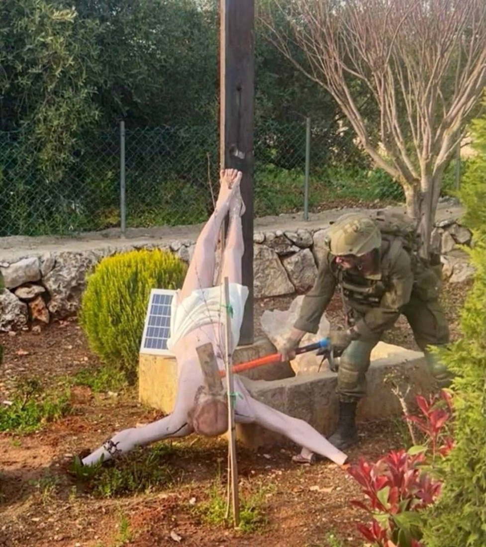 An Israeli soldier damages the head of a statue of Jesus, in Debel, Lebanon. (REUTERS)