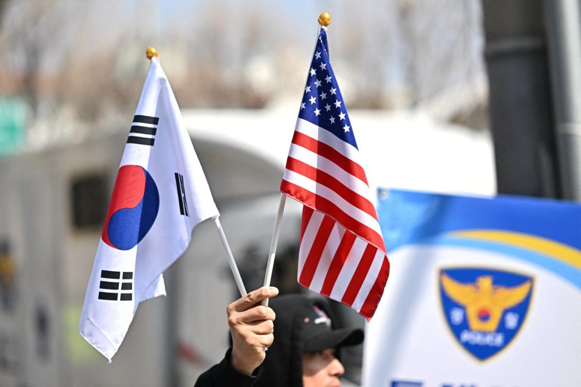 An individual holds the US and South Korean flags near the entrance of the Constitutional Court in Seoul on April 1, 2025. (AFP)