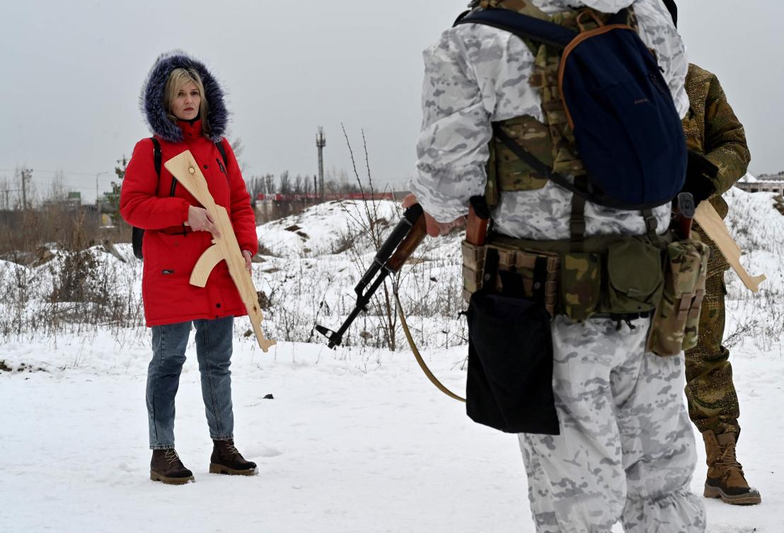A military instructor teaches civilians holding wooden replicas of Kalashnikov rifles, as they take part in a training session at an abandoned factory in the Ukrainian capital of Kyiv on February 6, 2022. (AFP)