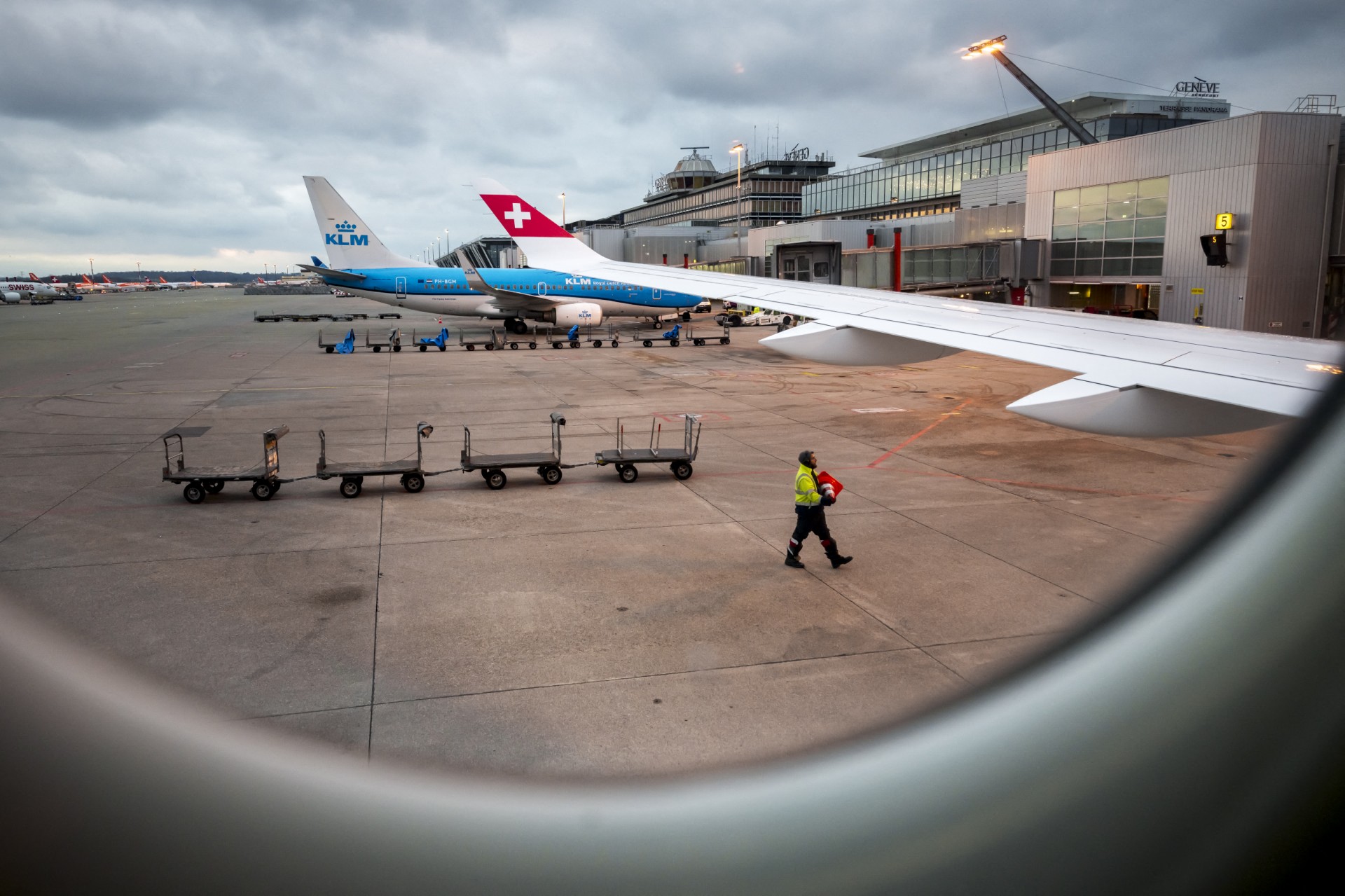 A staff member removes on the tarmac a traffic cone next to commercial planes of Swiss air lines and KLM at Geneva Airport on March 17, 2025. (AFP)