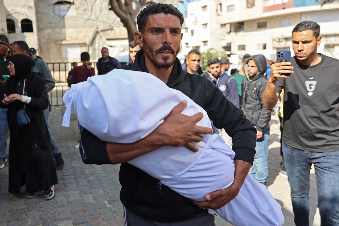 A man carries the body of a child from a hospital in Gaza City after an Israeli attack targeted residential areas near Kamal Adwan hospital in Beit Lahia. (AFP)
