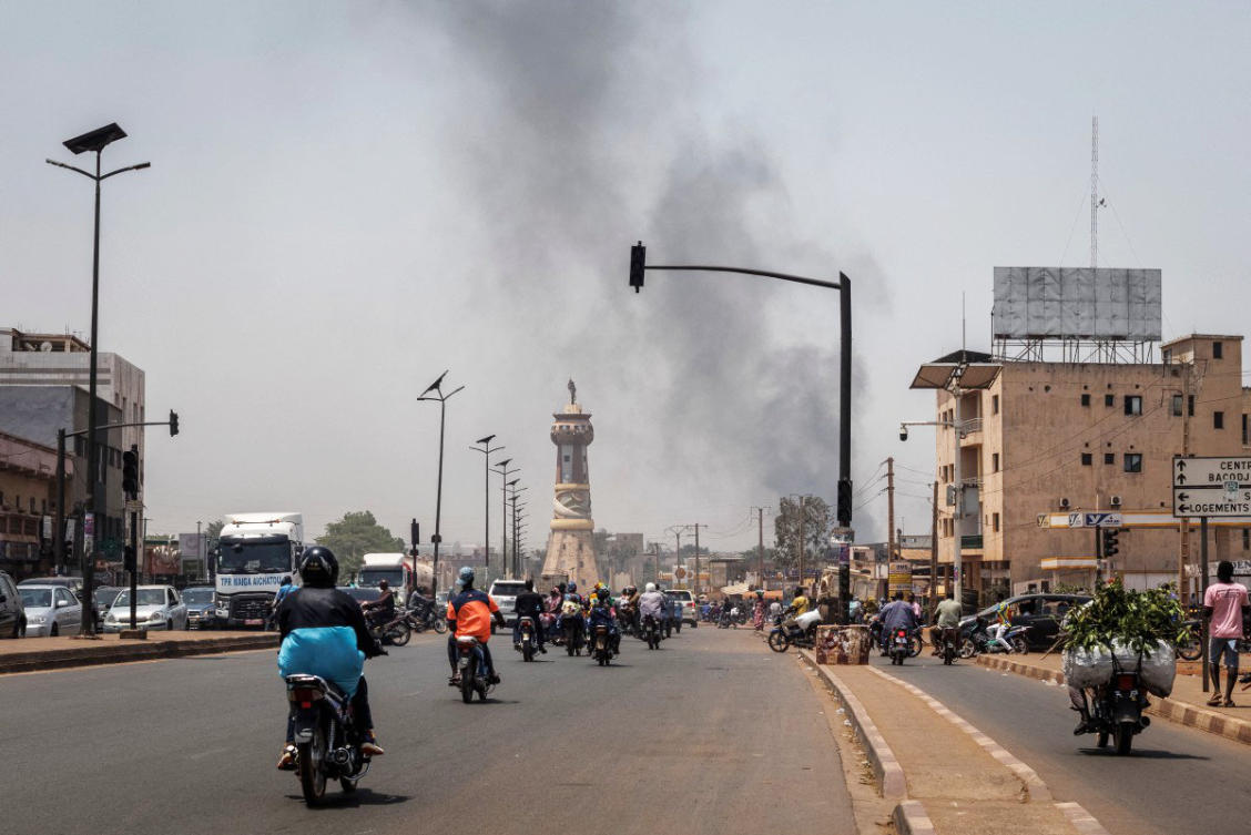 A column of black smoke rises above buildings as traffic passes the Africa Tower monument in Bamako on April 26, 2026. (AFP)