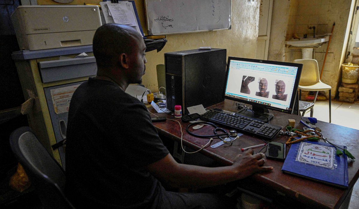 A Sudanese volunteer responsible for handling burial procedures for unidentified bodies in the capital, Khartoum, reviewing images of a victim at Omdurman's Al-Nao Educational Hospital. (AFP)