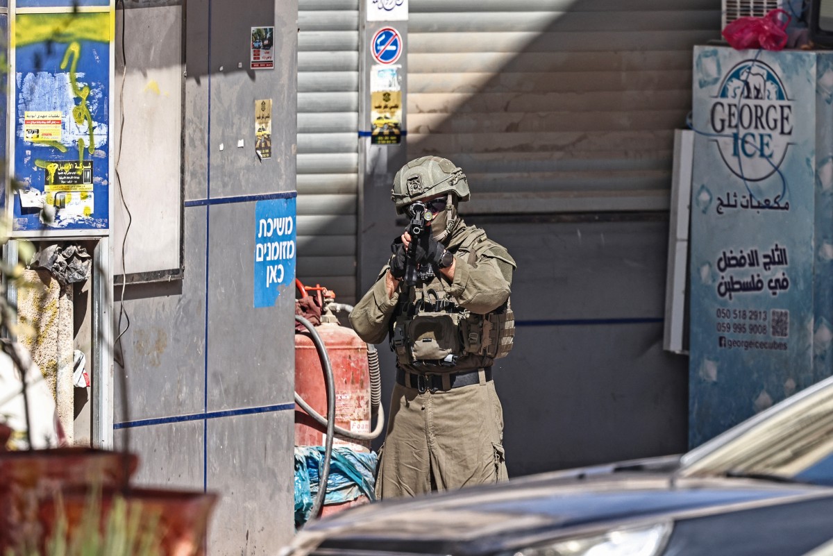 A member of Israeli security forces points his gun during a raid in the neighborhood of Kafr Aqab in the Israeli-occupied West Bank, April 27, 2026. (AFP)