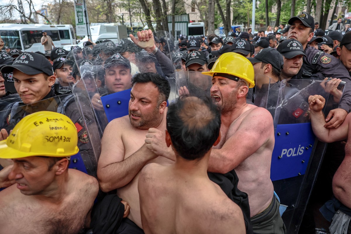 Protesters face riot-police officers during a topless rally staged by some 90 miners outside Turkiye’s Energy Ministry to demand unpaid wages in Ankara, April 27, 2026. (AFP)
