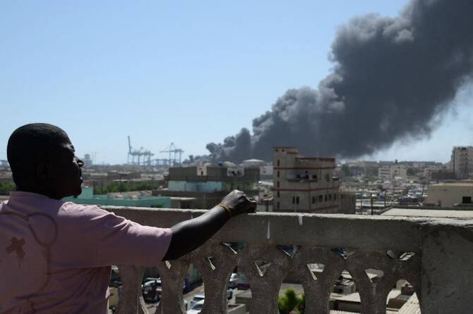 A man watches as smoke billows after a drone strike on the port of Port Sudan last year. (AFP/File)