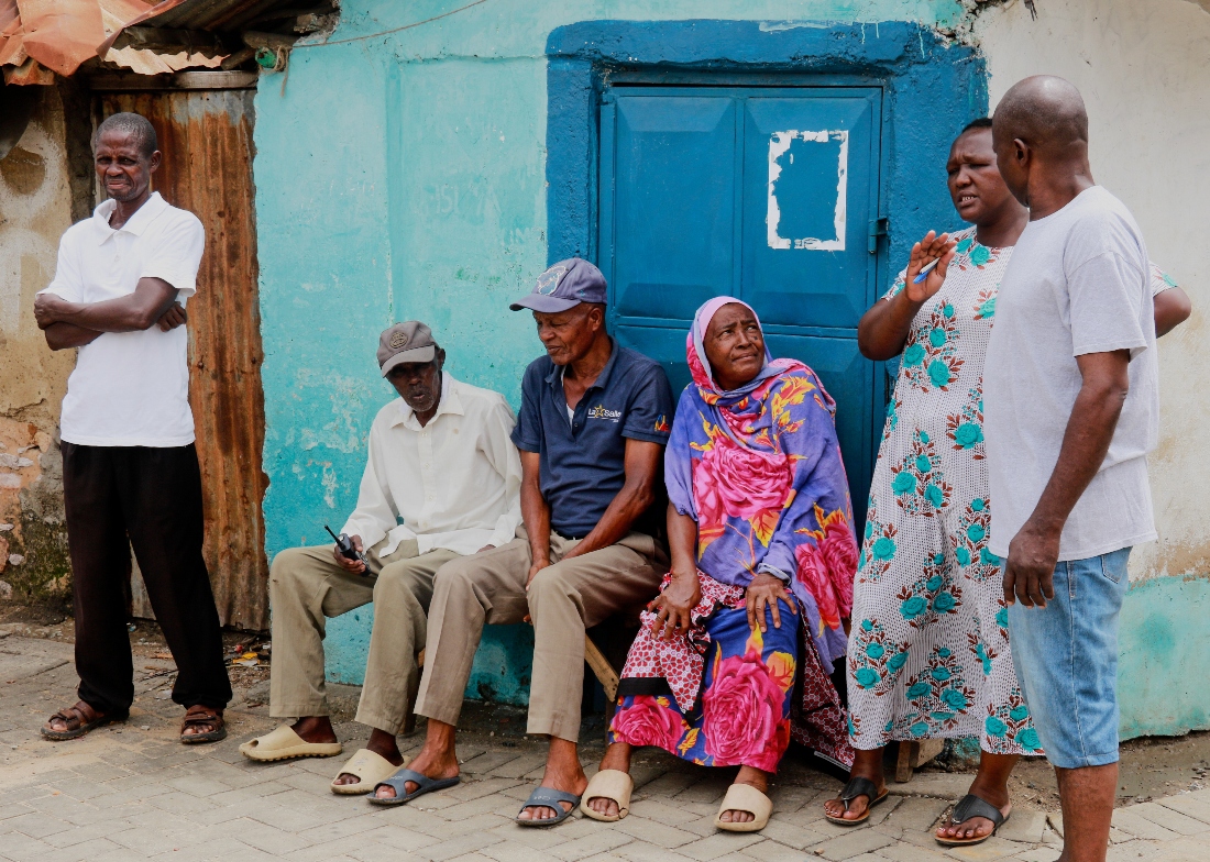 Locals sit and stand along a street in Owino Uhuru village, an informal settlement in Mikindani, Mombasa County, Kenya. (AP)