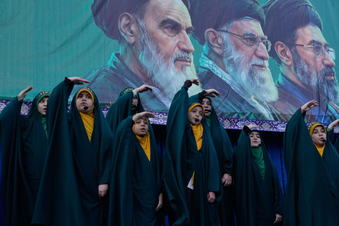 Girls sing a song as they show the movement of missiles with their hands next to the portraits of the late Iranian revolutionary founder Ayatollah Khomeini and his successors (AP Photo/Vahid Salemi)