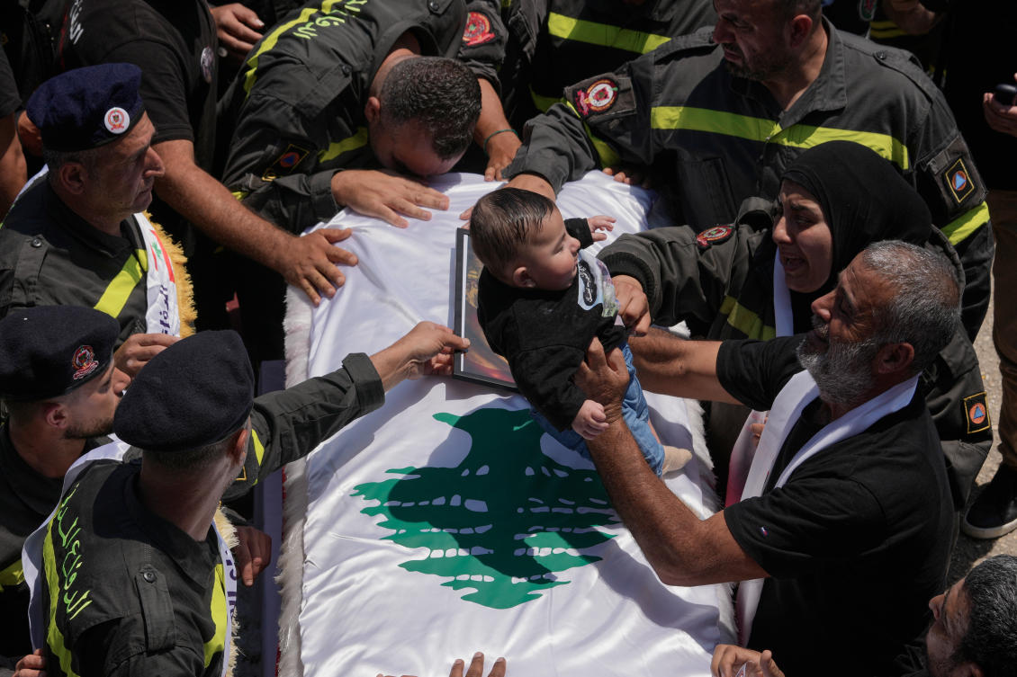 The five month-old son of Lebanese Civil Defense worker Hussein Ali Satti sits on his father’s coffin during his funeral on Thursday. Satti was killed alongside two colleagues in an Israeli strike on Tuesday. (AP)