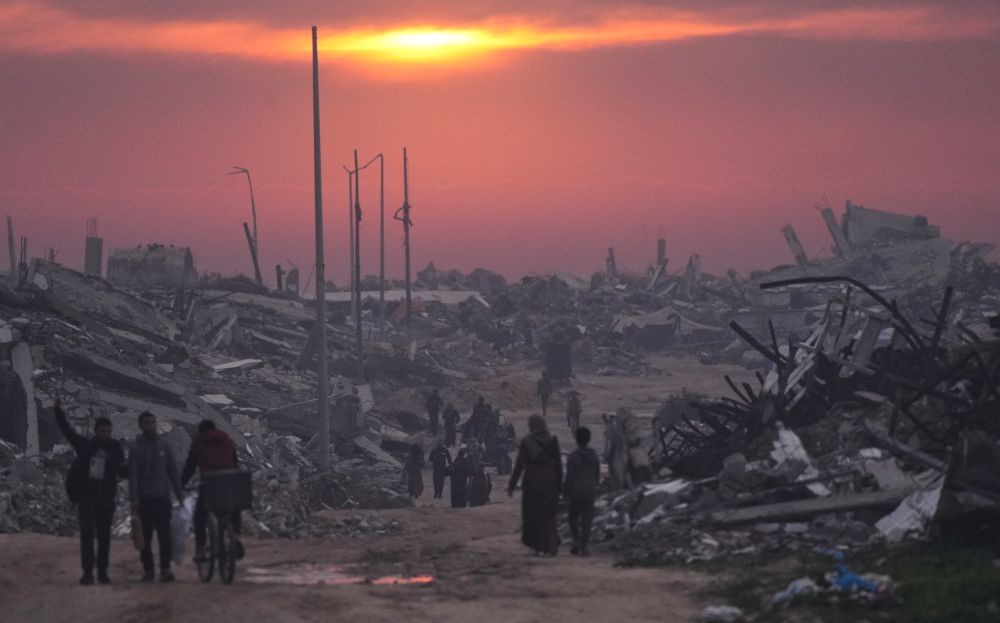 Palestinians walk through the ruins of destroyed buildings as the sun sets over Gaza City, Sunday, Jan. 4, 2026. (AP Photo)
