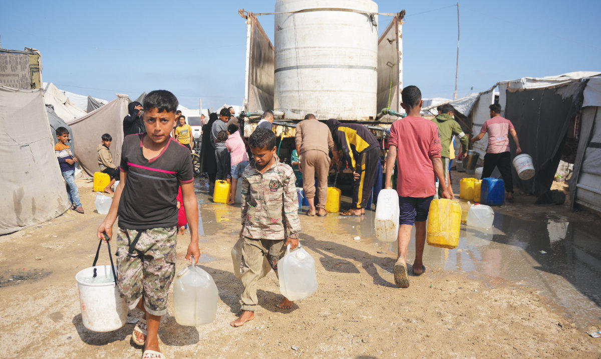 Displaced Palestinians gather on Thursday to collect water from a truck at a makeshift tent camp in Khan Younis, southern Gaza Strip. (AP)
