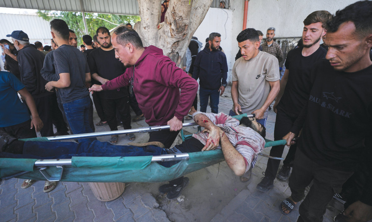 Palestinians carry the body of Salah Al-Shambari into Al-Shifa Hospital after he was killed in an Israeli airstrike in Gaza City on Tuesday. (AP)
