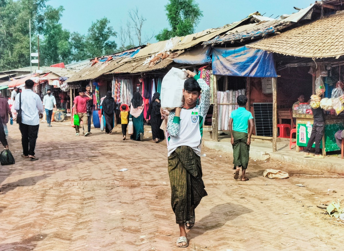 A Rohingya refugee carrying a sack walks across a market at the Kutupalong refugee camp in Ukhia on January 12, 2026. (File/AFP)