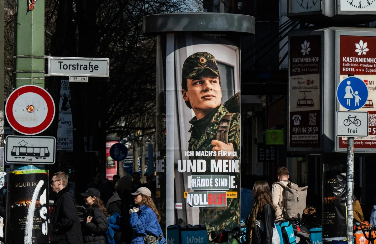An advertising poster for the German armed forces (Bundeswehr) is altered to read: "...and my hands are covered in blood", in Berlin, Germany. (AFP)