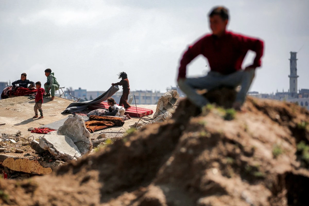 Children sit on the rubble of destroyed buildings at the Bureij camp for Palestinian refugees in the central Gaza Strip, March 27, 2026. (AFP)
