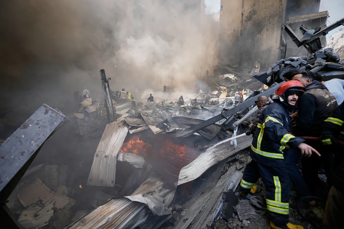 Firefighters, first responders, and volunteers work on smoldering debris at the site of an Israeli airstrike that struck an apartment building in Beirut Wednesday. (AP)