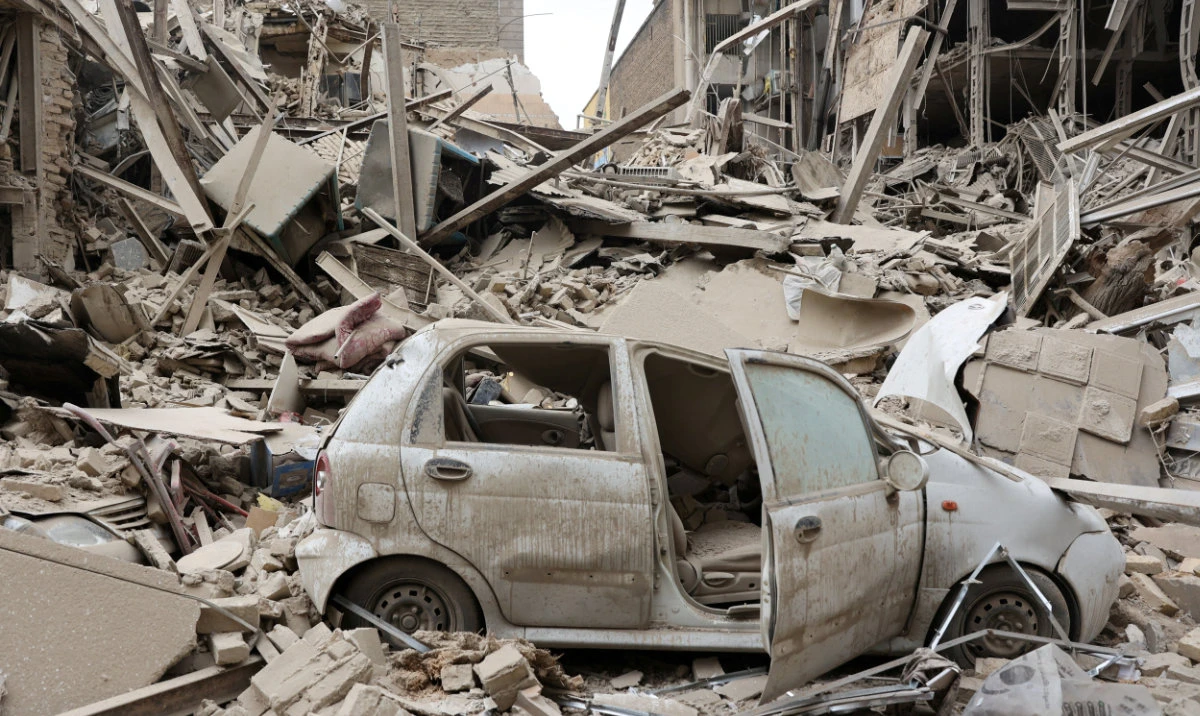 A destroyed vehicle amid rubble at the site of a US-Israeli strike on a residential building in a Tehran neighborhood. (Reuters)
