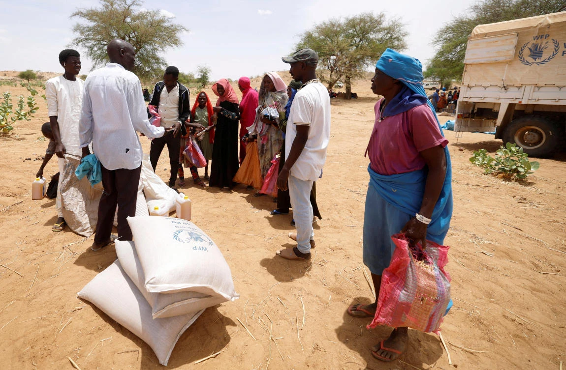 Halime Adam Moussa, a Sudanese refugee who is seeking refuge in Chad for a second time, waits with others to share food portions, received from World Food Programme (WFP), near the border between Sudan and Chad in Koufroun, Chad, May 9, 2023. (Reuters/File)