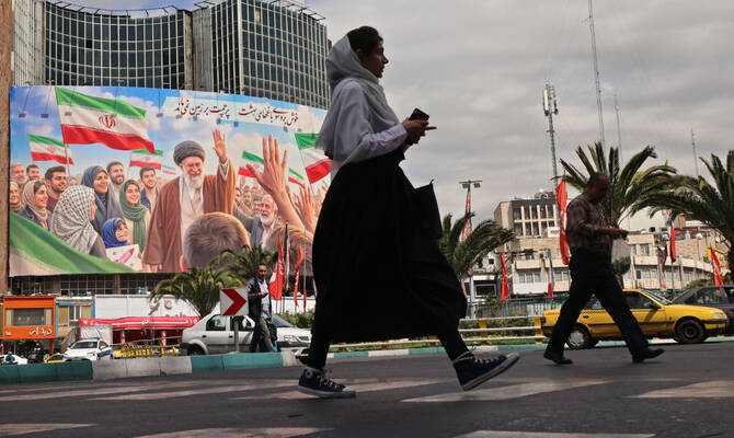 Commuters make their way past a giant billboard of slain Iranian supreme leader Ayatollah Ali Khamenei in Tehran. (AFP)