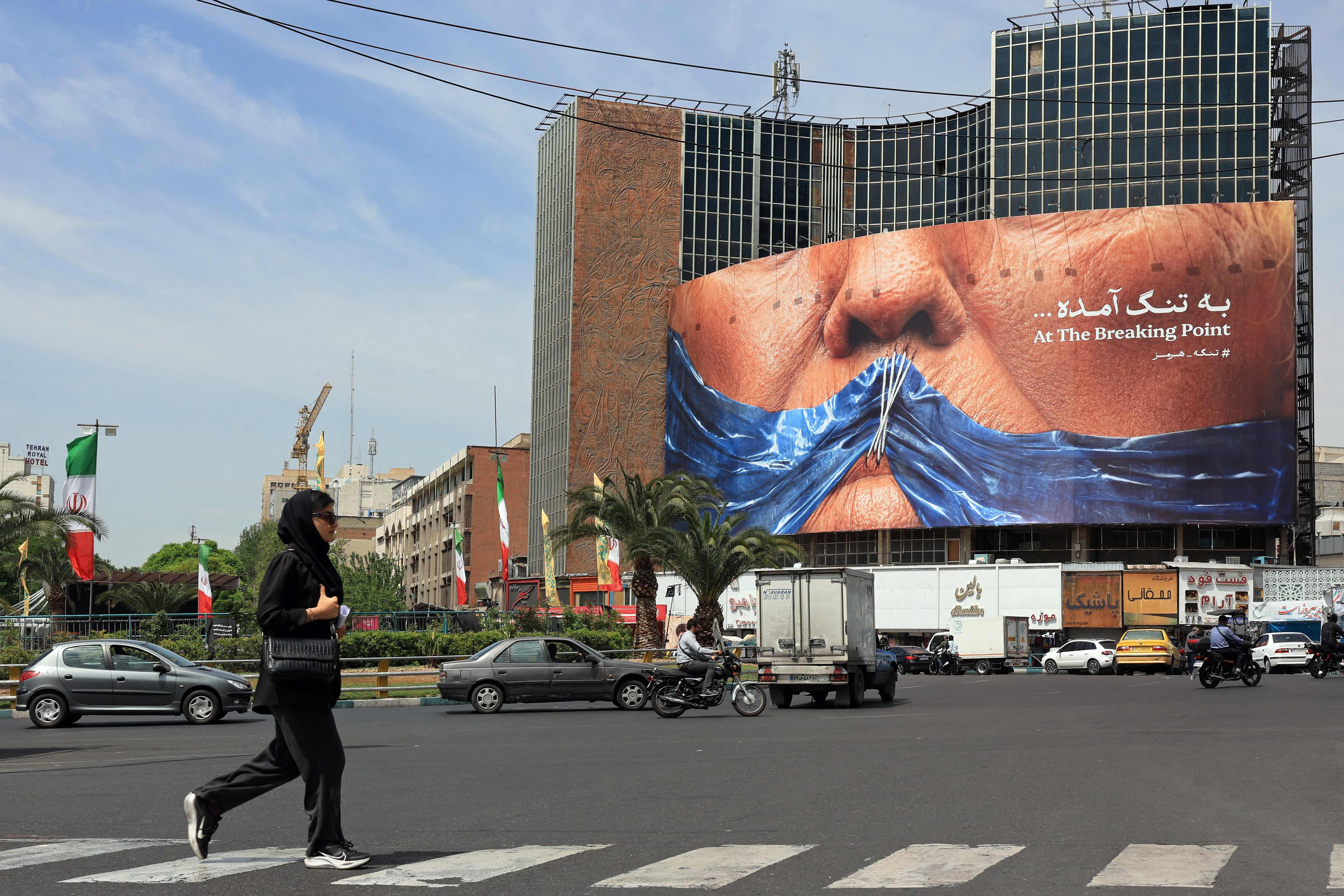 A woman walks past an anti-US billboard referring to President Donald Trump and the Strait of Hormuz, installed on a building at the Valiasr Square in Tehran on May 2, 2026. A senior Iranian military officer said on May 2 that renewed fighting between the US and Iran was “likely.” (AFP)