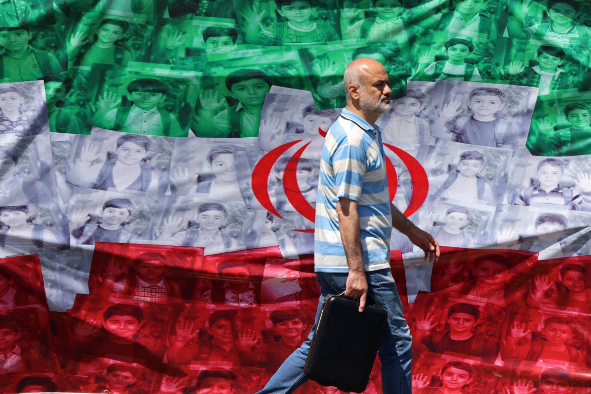Above, a man walks past an Iranian flag installed along the roadside in Tehran on April 29, 2026. (AFP)