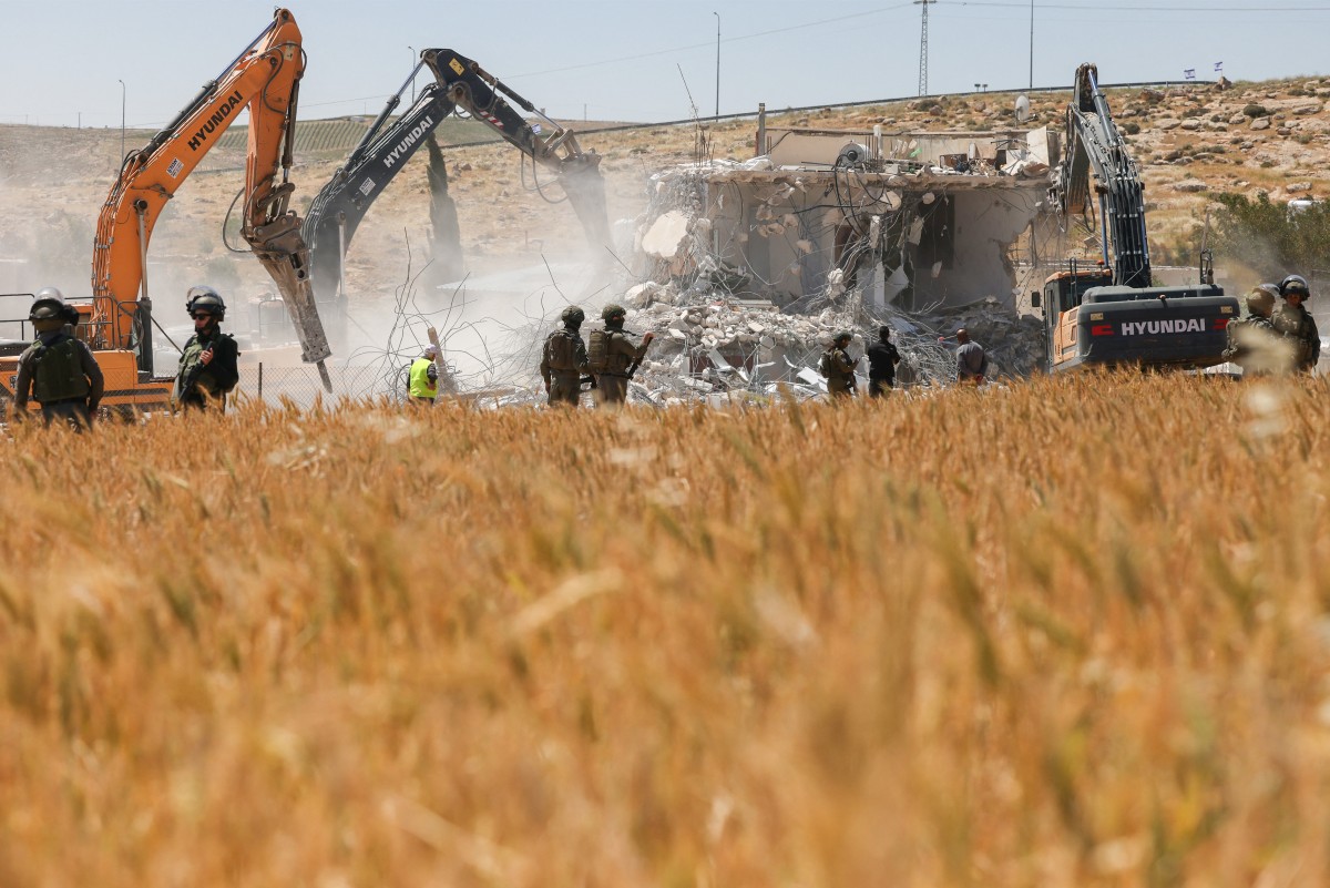 Israeli security forces stand guard as excavators demolish a Palestinian house that was built without a permit, in the village of al-Dirat near Yatta town in the occupied West Bank city of Hebron, May 4, 2026. (Files / AFP)