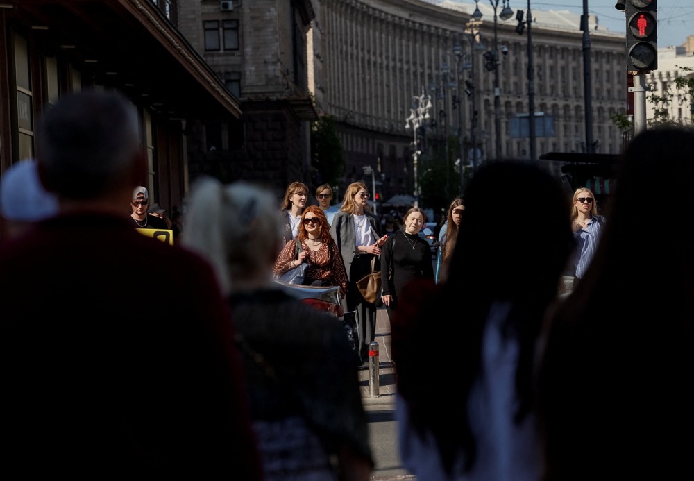 People wait to cross a street on an untypical hot spring day, amid Russia’s attack on Ukraine, in central Kyiv, Ukraine. (Reuters)