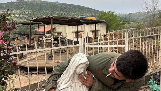 A soldier smokes and pushes another cigarette onto the mouth of a statue of the Virgin Mary in Debel, Lebanon, in this picture released May 6, 2026 obtained from social media. (Reuters)