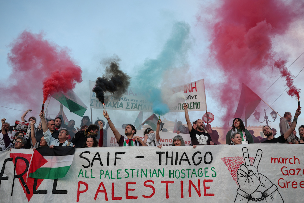 Protesters hold flares with the colours of the Palestinian flag, during a demonstration calling for the release of Saif Abu Keshek and Brazilian Thiago Avila, who were detained aboard a Gaza-bound flotilla that was intercepted by Israeli forces in international waters near Greece, while an Israeli court extended their detention until May 10, in Athens, Greece, May 5, 2026. (Reuters)