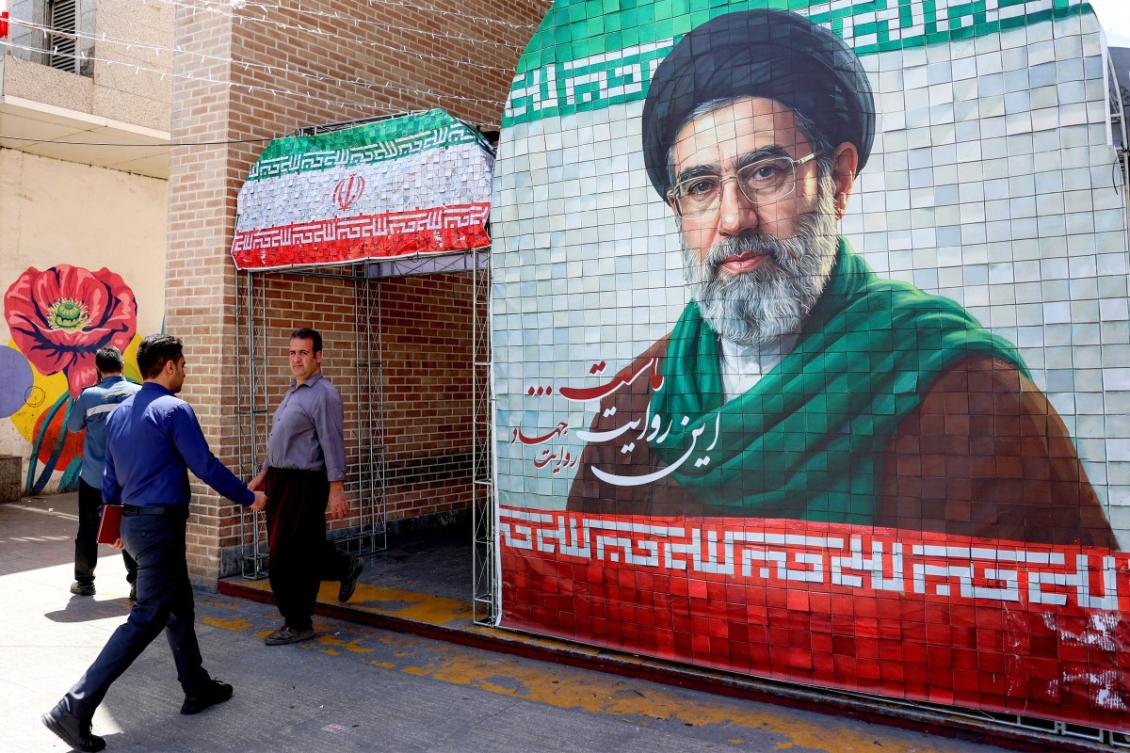 A man walks past a banner depicting Iran’s current supreme leader Ayatollah Mojtaba Khamenei along a street Tehran on May 6, 2026. (AFP)