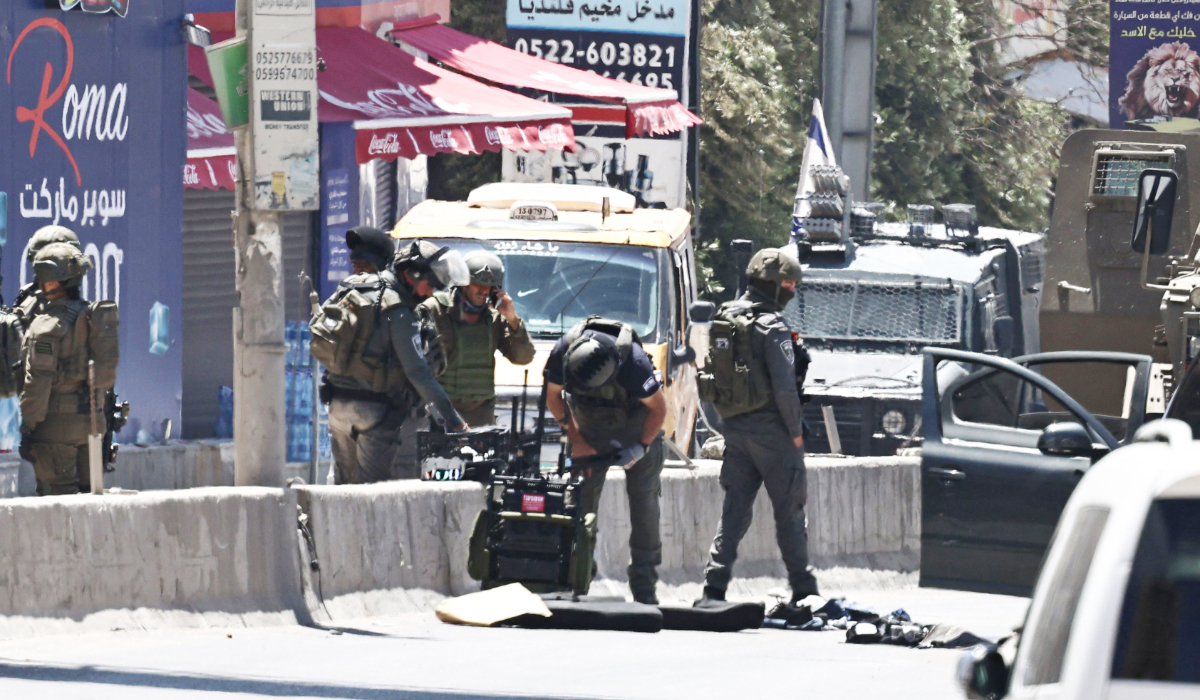 Israeli army soldiers inspect the site where a Palestinian was killed during an Israeli raid on Qalandia, south of the city of Ramallah, in the Israeli-occupied West Bank, on May 11, 2026. (AFP)