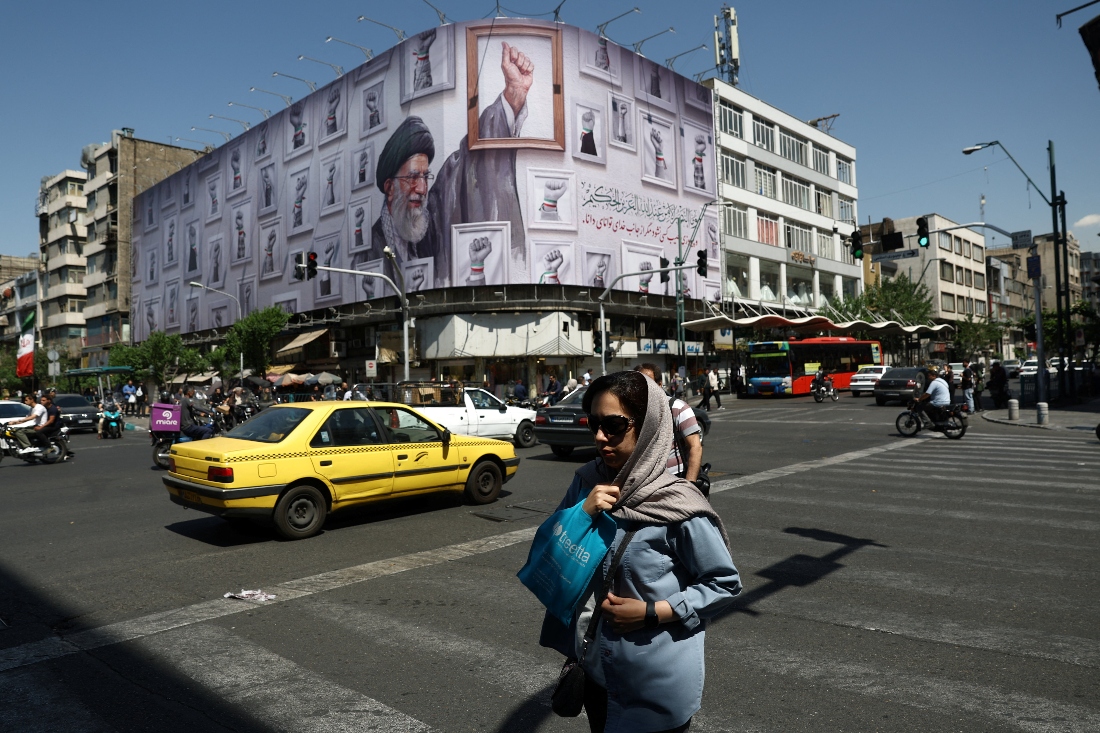 A woman walks near a billboard featuring an image of the late Supreme Leader of Iran, Ayatollah Ali Khamenei, in Tehran, Iran. (WANA)