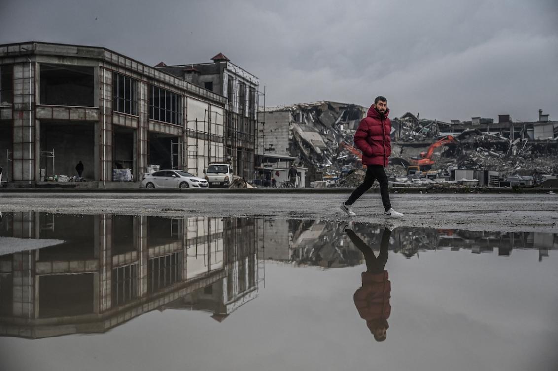 A man walks past a flooded street as diggers work to clean the rubble of collapsed buildings eleven months after a 7.8-magnitude earthquake jolt and aftershocks wiped out swathes of Turkey's mountainous southeast, in Antakya on January 12, 2024. (FILE/AFP)