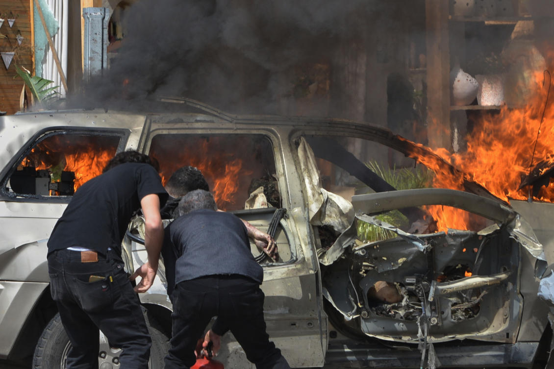 A person is seen inside a burning vehicle as men attempt to put out the fire after an Israeli airstrike hit a car in the coastal town of Barja, south of Beirut, Lebanon, Wednesday, May 13, 2026. (AP Photo/Mustafa Jamalddine)
