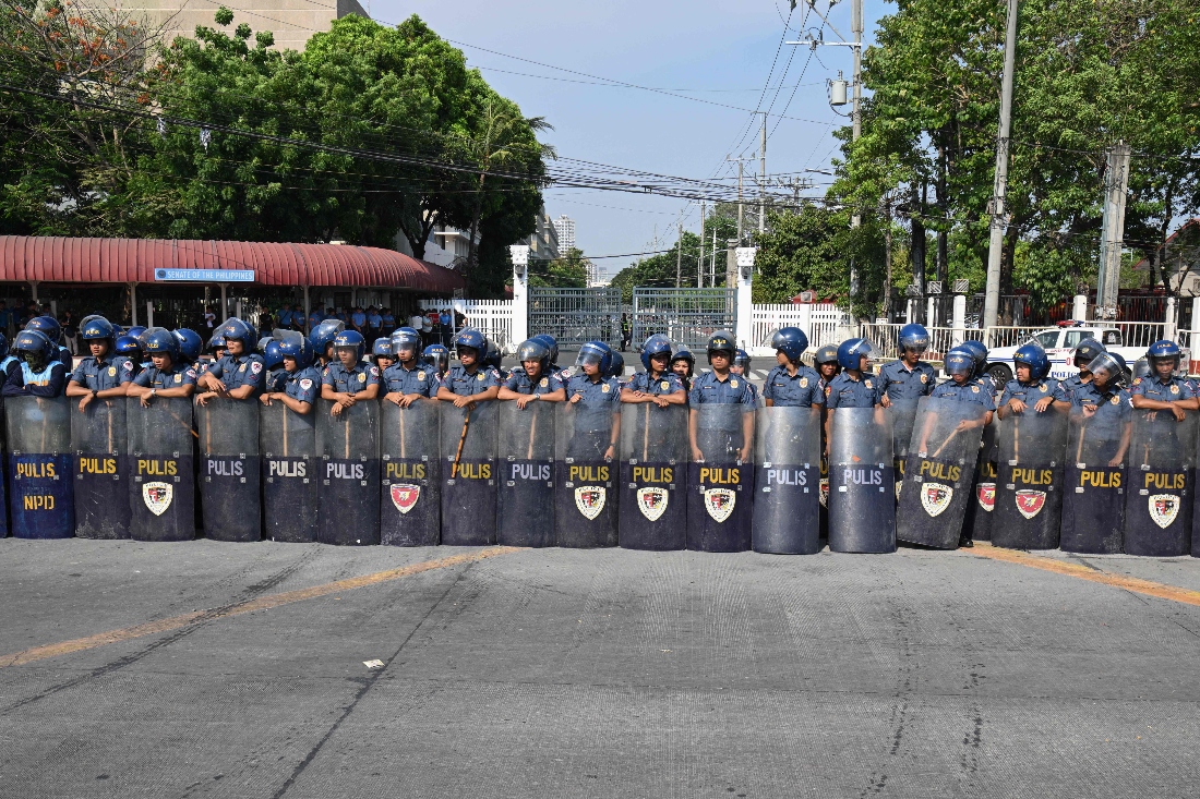 Riot police stand guard in front of the Senate gate in Manila, Philippines. (AFP)
