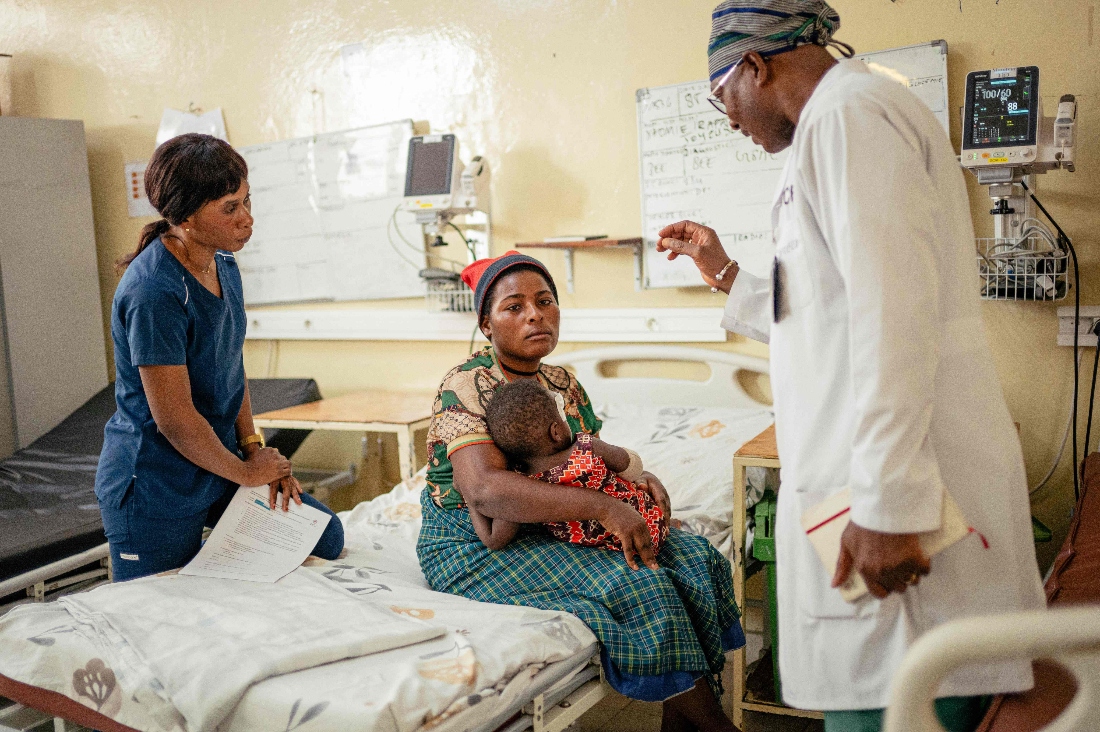 Doctor Soumah Sekou Amadou, a senior surgeon working with the International Committee of the Red Cross (ICRC), speaks to Esperance Bahati holding her baby, who was wounded during the bombing of Mushaki, in a ward at at the ICRC supported CBCA Hospital in Goma, Congo. (AFP)