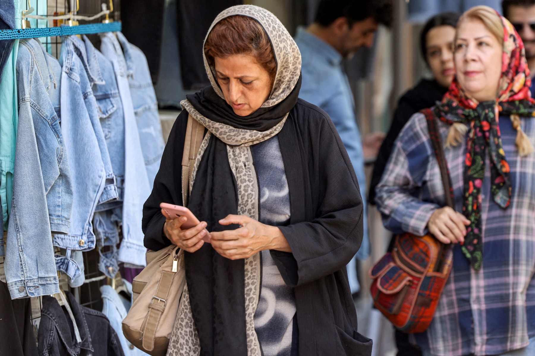 A woman browses a phone while walking along a street in Tehran, Iran. (AFP)