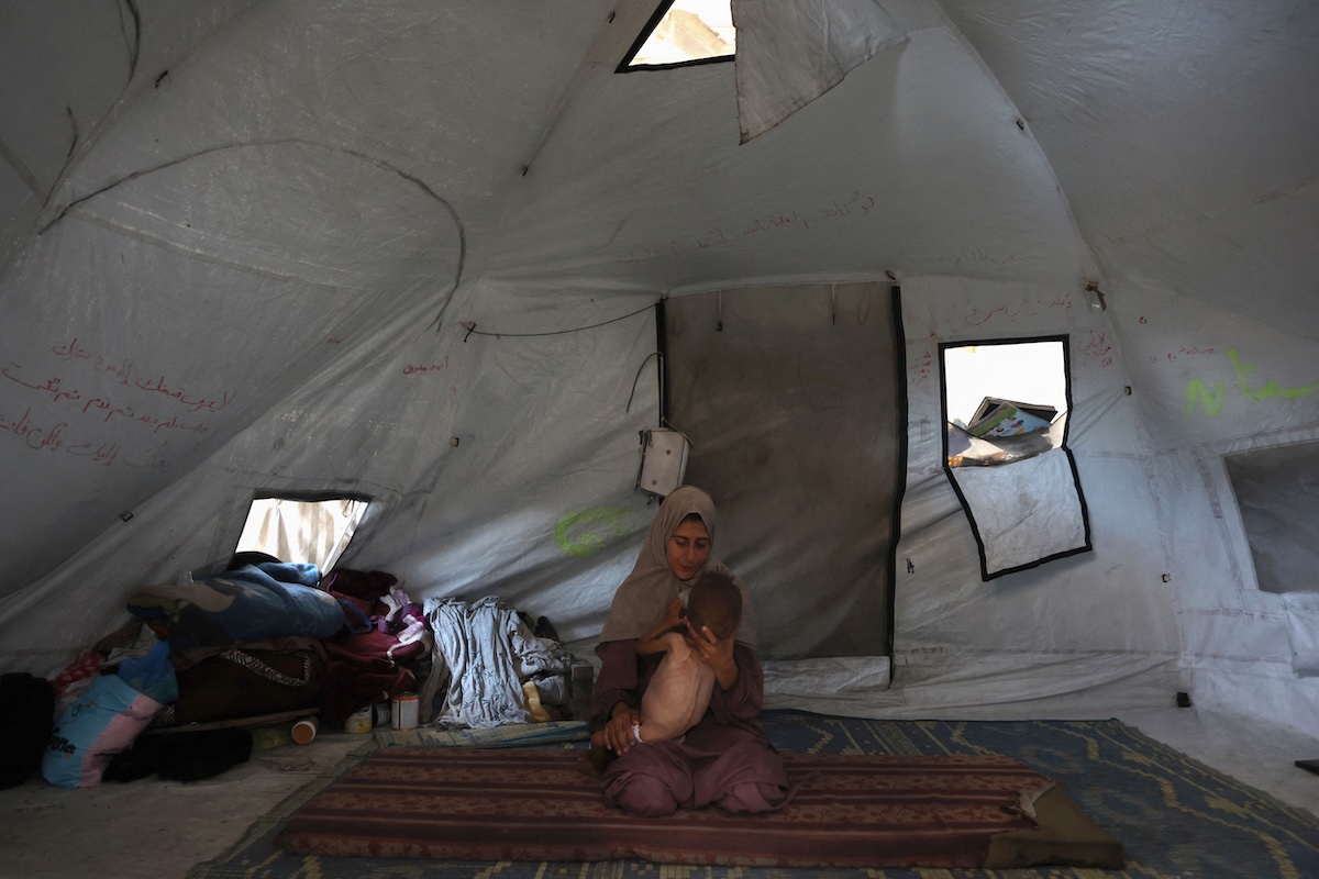 Hidaya, a 31-year-old Palestinian mother, cradles her sick 18-month-old son Mohammed al-Mutawaq, who is also displaying signs of malnutrition, inside their tent at the Al-Shati refugee camp, west of Gaza City, on July 24, 2025. (FILE/AFP)