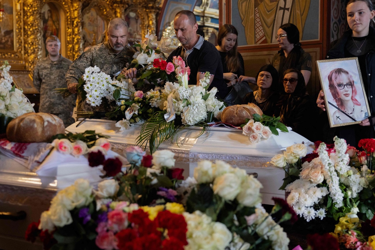 Relatives and friends mourn at the coffins of 12-year-old and 17-year-old sisters Liubava and Vira Yakovleva, who were killed in a Russian attack that killed 24 people on May 14, during a funeral ceremony at the Saint Michael's Golden-Domed Monastery in Kyiv on May 19, 2026, amid the Russian invasion of Ukraine. (AFP)