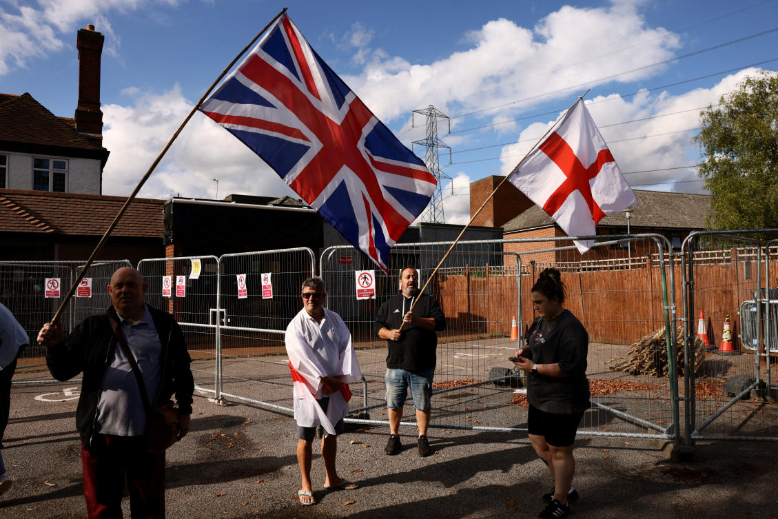 Protesters hold the Union Jack and St George's flags outside the Bell Hotel, Essex after the British government challenged a court ruling requiring asylum seekers to be temporarily evicted from the hotel in Epping, Britain, August 29, 2025. (Reuters)