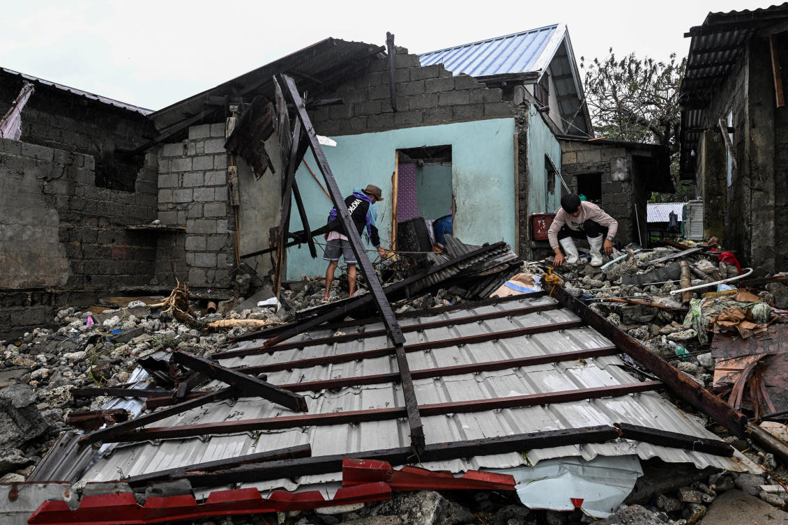 Residents look for belongings in front of their house damaged by storm surges after Typhoon Fung-wong hit the coast of Alacan, Pangasinan on Nov. 11, 2025. (Reuters)