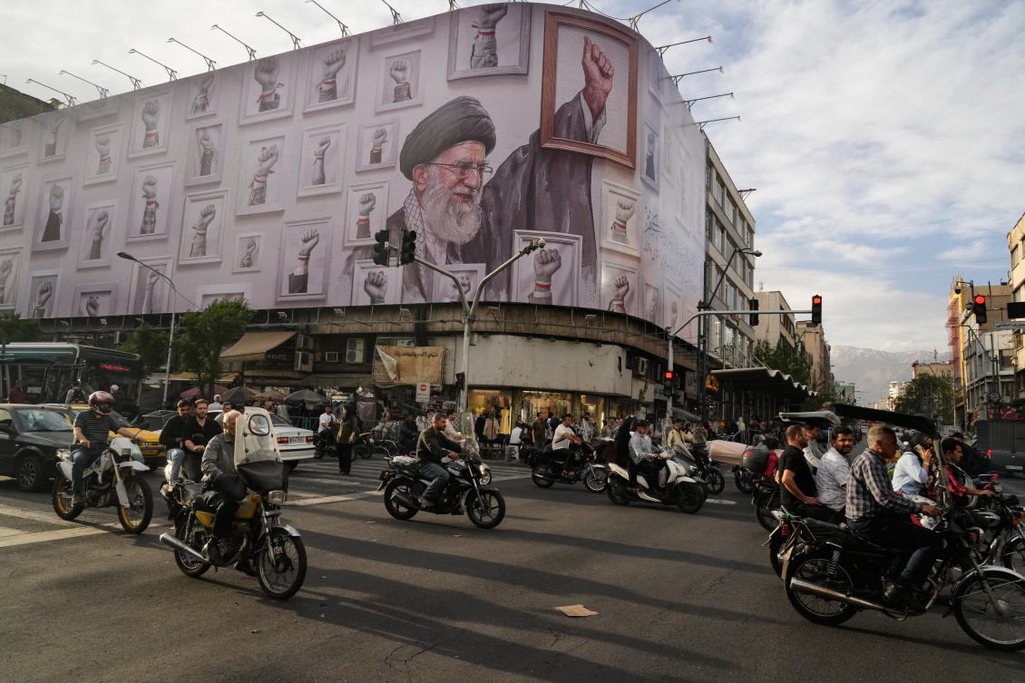 FILE - Motorbikes drive past a billboard showing the late Iranian Supreme Leader Ayatollah Ali Khamenei, who was killed in the U.S. and Israel strikes on Feb. 28, in downtown Tehran, Iran, May 6, 2026. (AP Photo/Vahid Salemi, File)