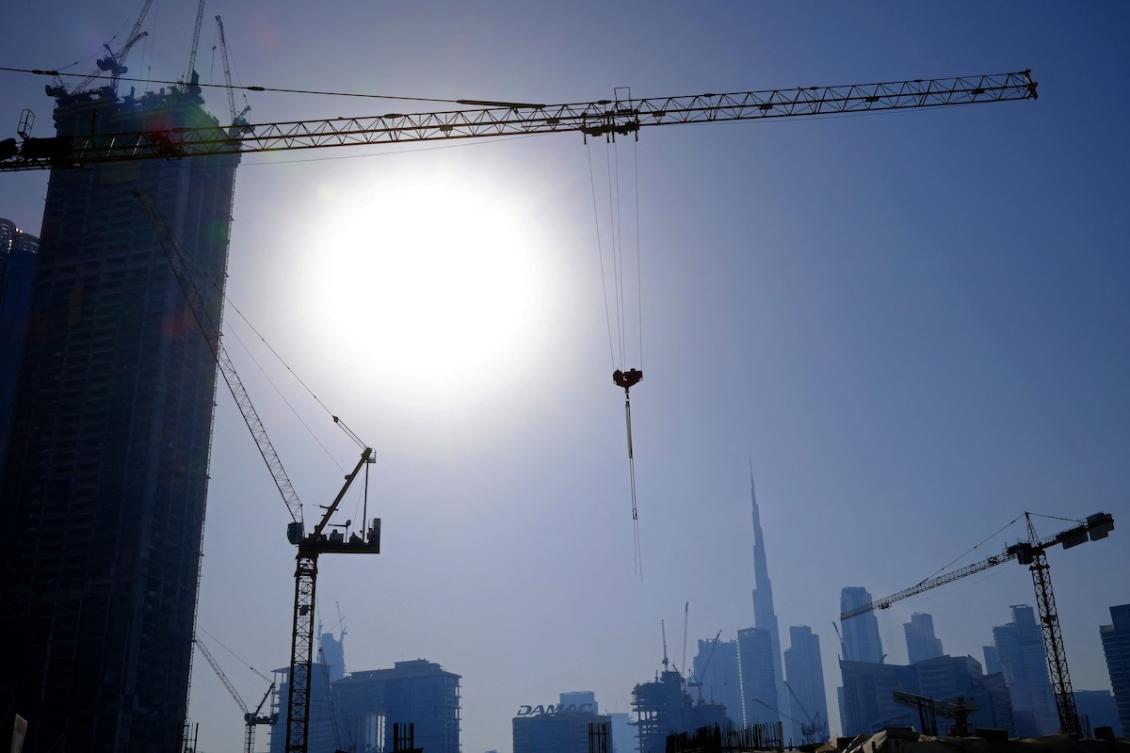 Cranes at a construction site are silhouetted against Burj Khalifa, the world’s tallest building and the Dubai skyline, on May 13, 2026. (FILE/AFP)
