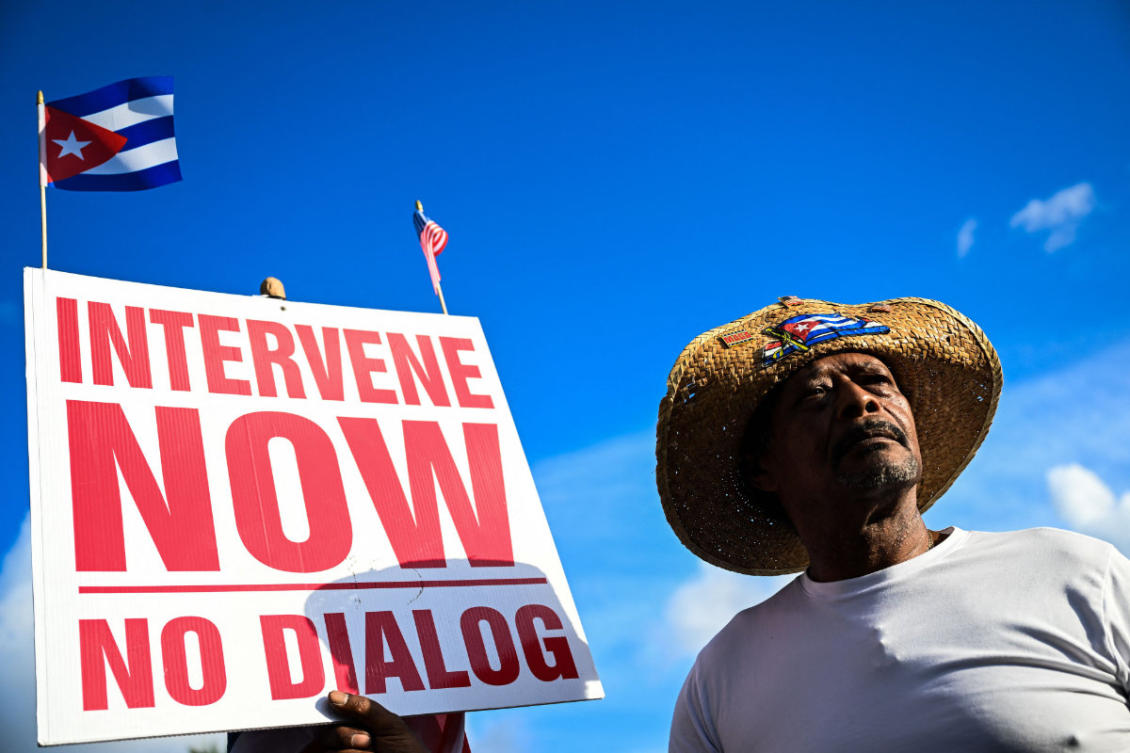 A man holds a sign outside Versailles Restaurant in support of charges announced by US federal prosecutors against the former Cuban president in Miami, Florida, on May 20, 2026. (AFP)