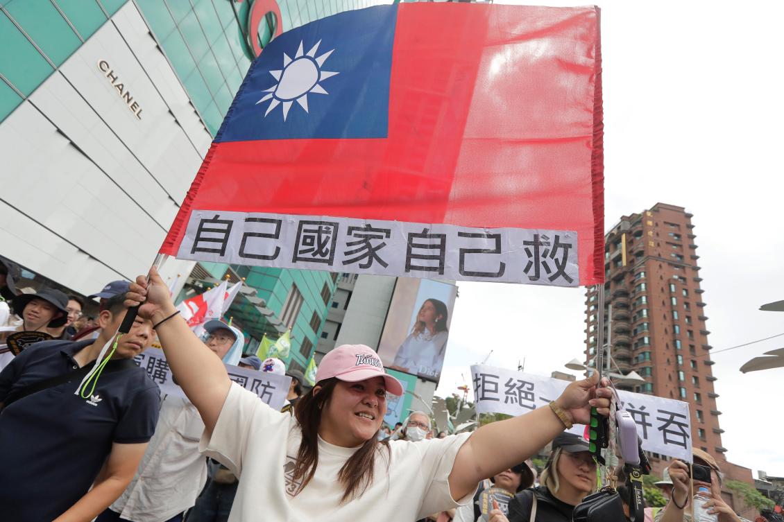 Above, a woman holds up Taiwan’s flag with a slogan reading, “Save our own country!” in Taipei on May 23, 2026. (AP)