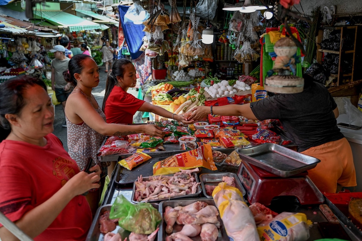 A woman gives change to a customer at a market in Manila on Oct. 5, 2023. (AFP file photo)