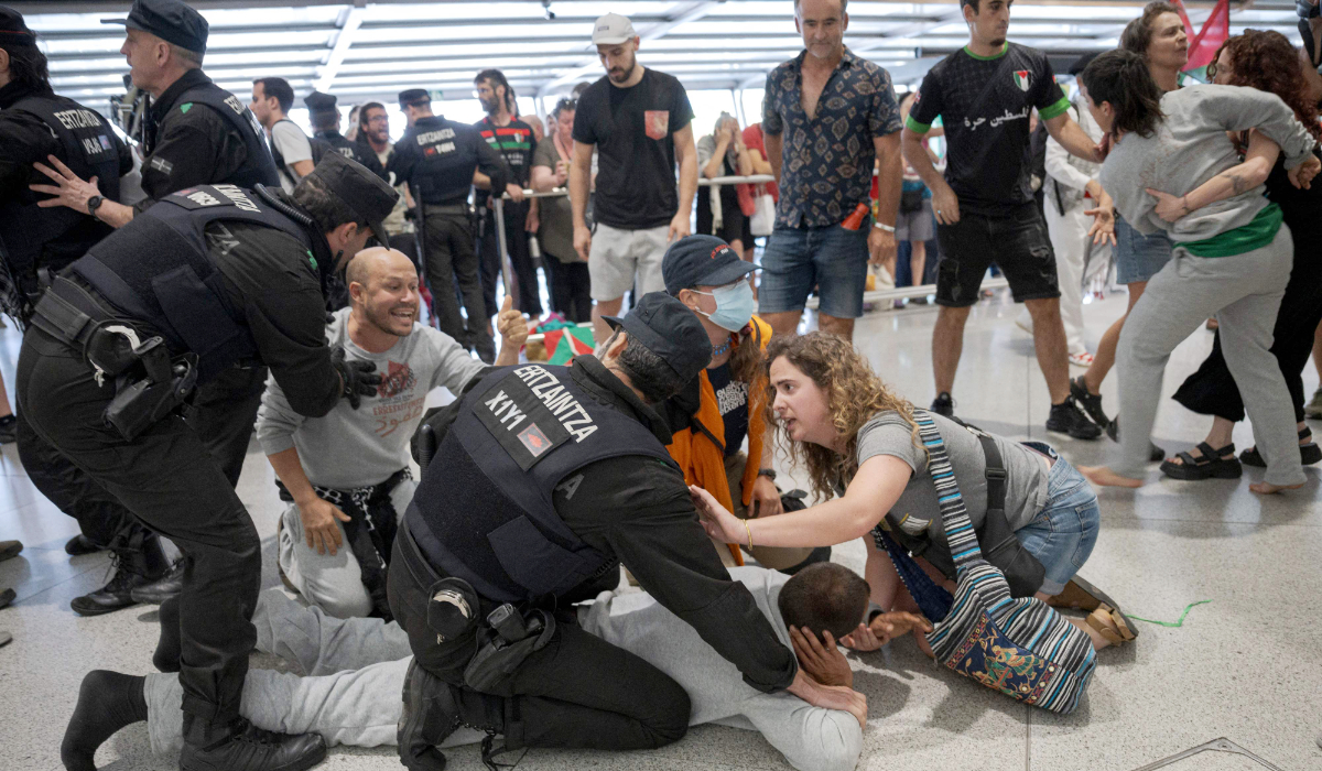 Basque police officers detain members of the Global Sumud Flotilla upon their arrival at Bilbao airport on May 23, 2026. (AFP)