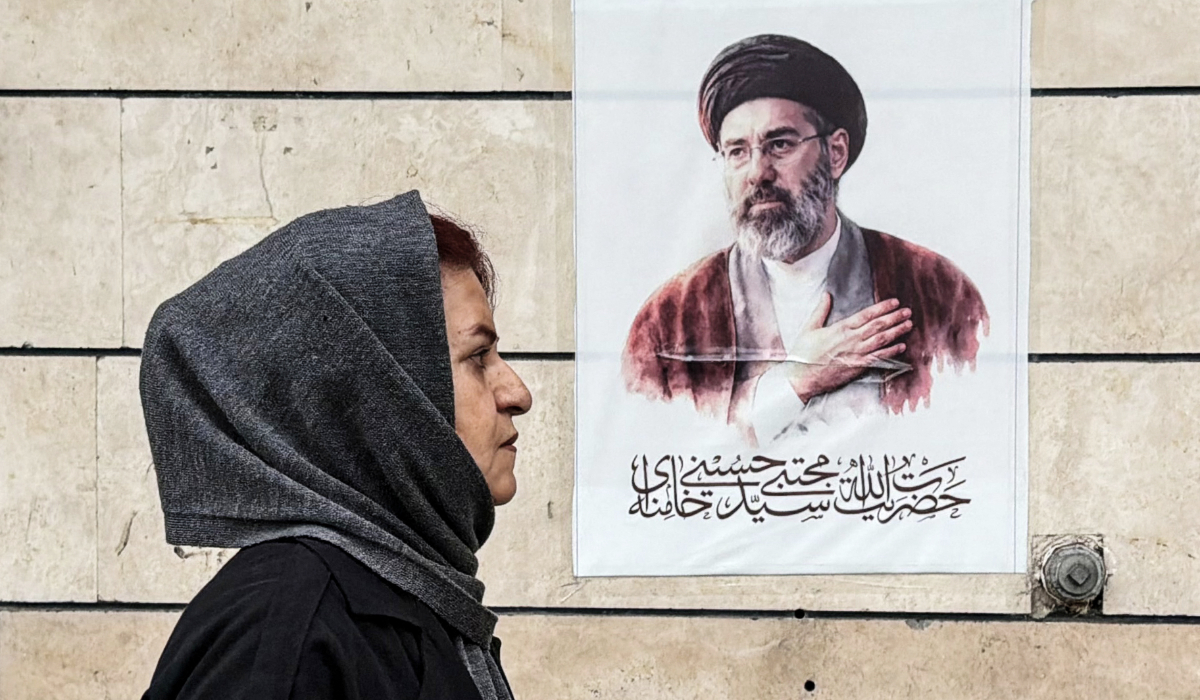 An Iranian woman walks past a poster featuring a portrait of Mojtaba Khamenei, Iran’s new Supreme Leader, in the capital Tehran on April 13, 2026. (AFP)